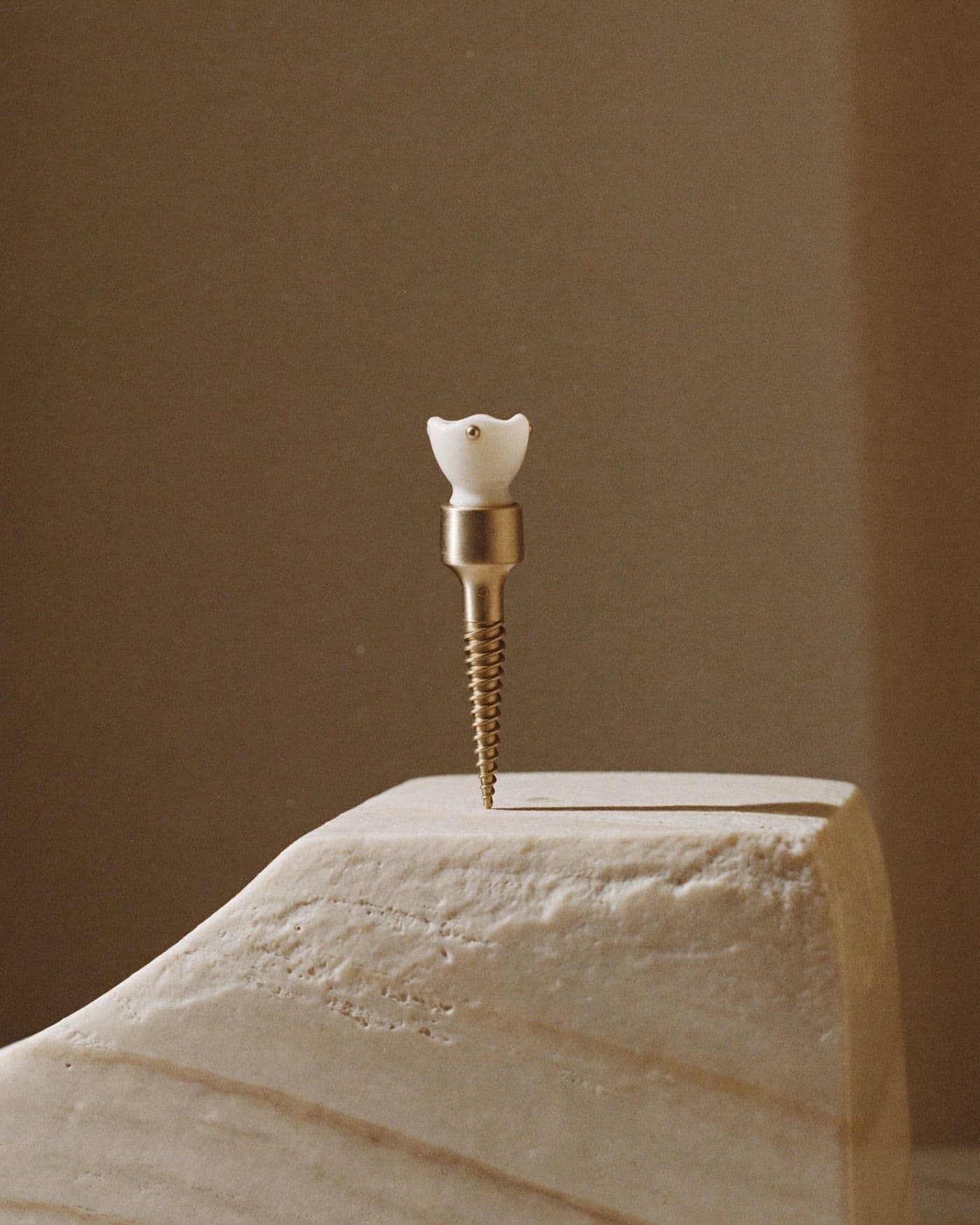 Tytanowy implant zębowy z ceramiczną koroną na kamiennym postumencie